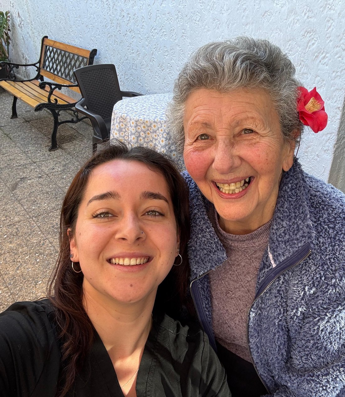 Kinesióloga de Vínculo Senior junto a una persona mayor, sonriendo en el patio de su hogar
